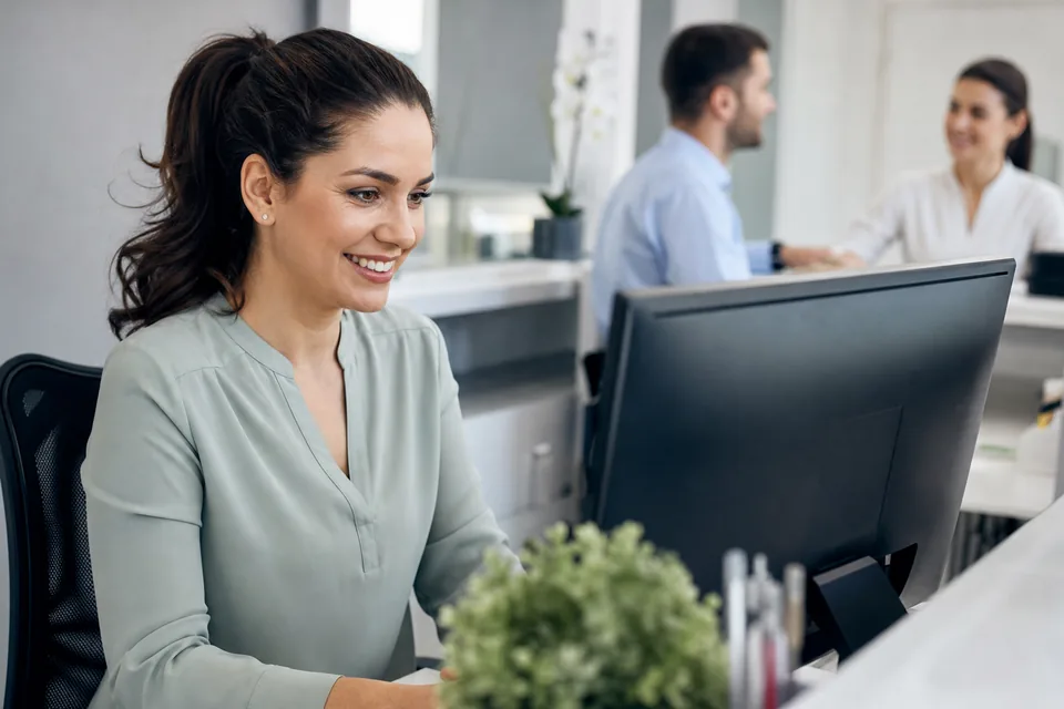 Dental office manager confirming a scheduled text blast on a desktop monitor at the front desk
