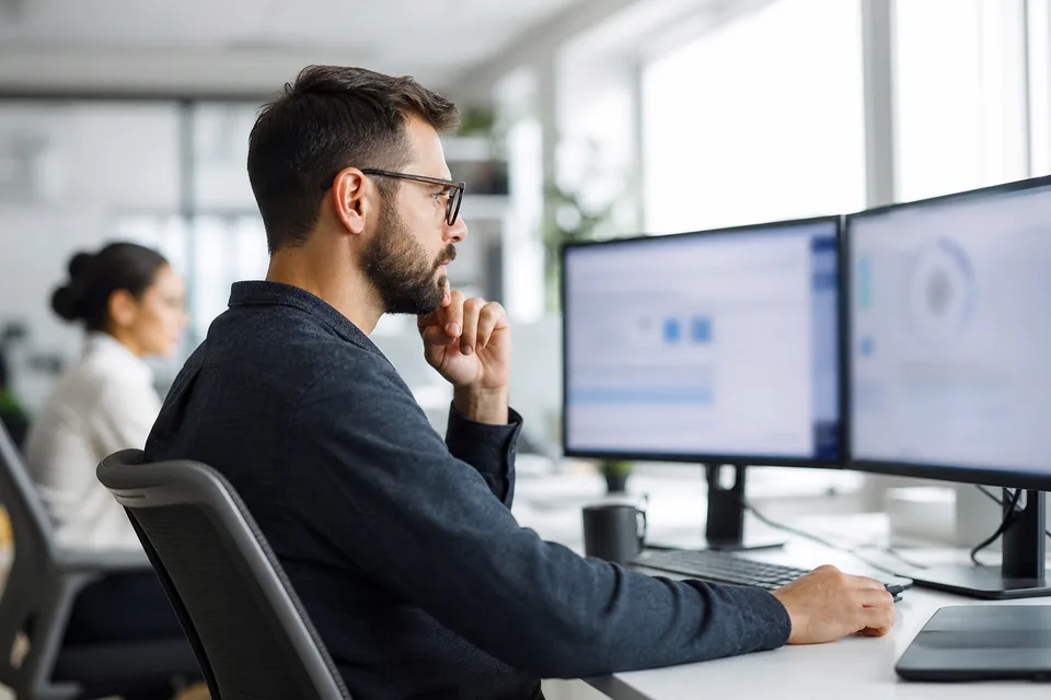 Revenue operations manager mapping CRM fields on a dual monitor setup in a bright office