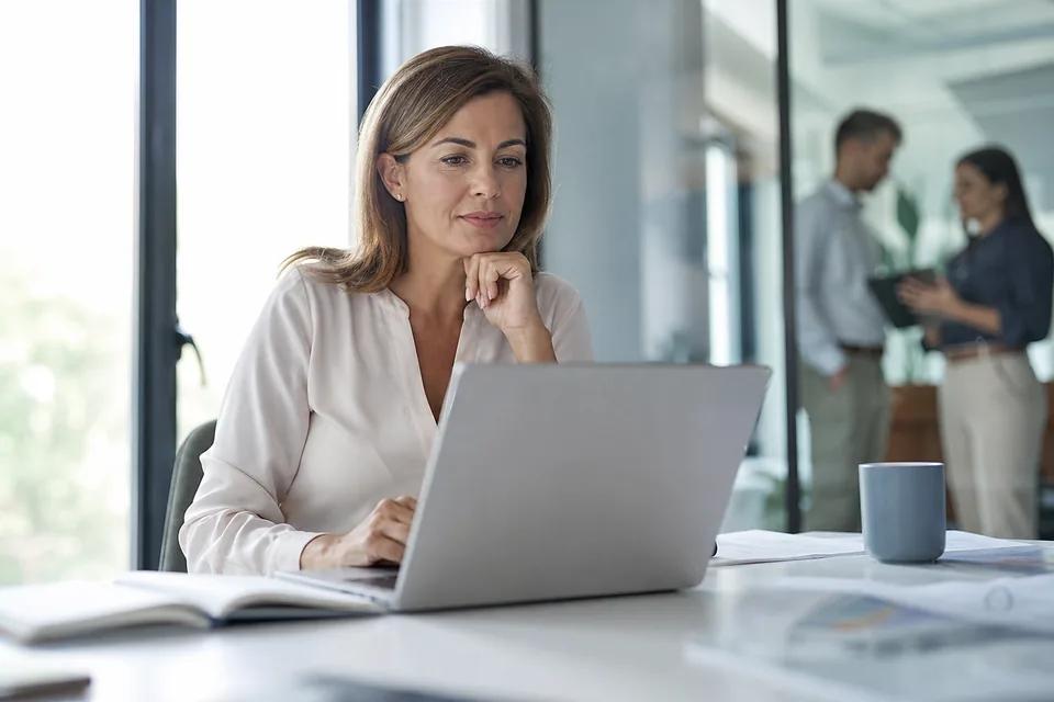 Office manager reviewing a scheduled mass text campaign on a laptop at a bright desk