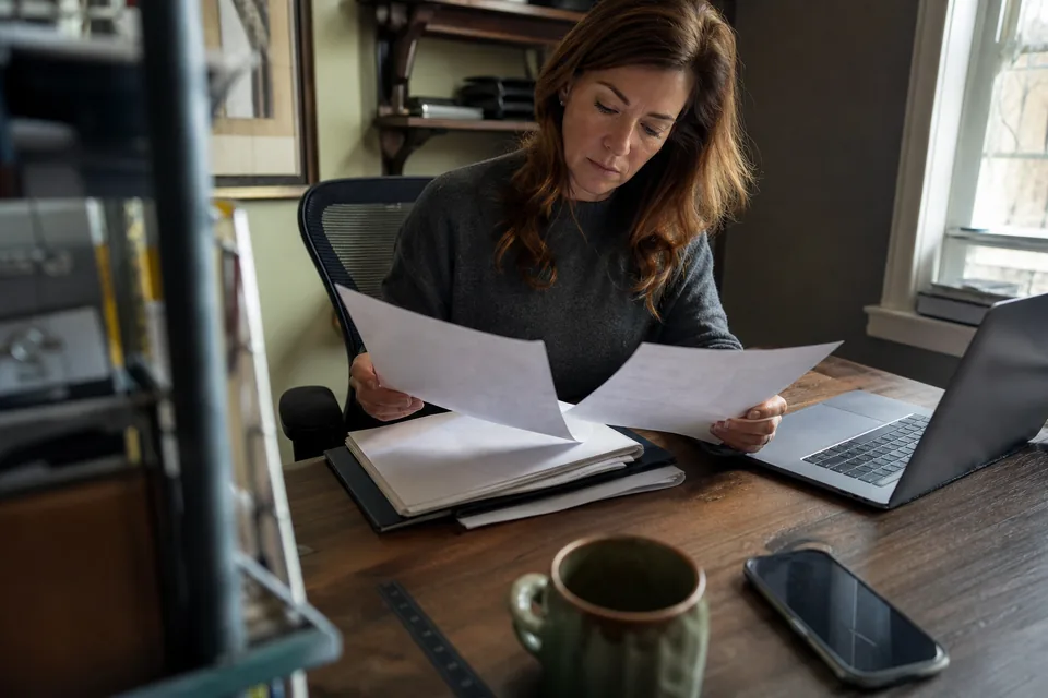 Business owner comparing two monthly texting software invoices at her desk