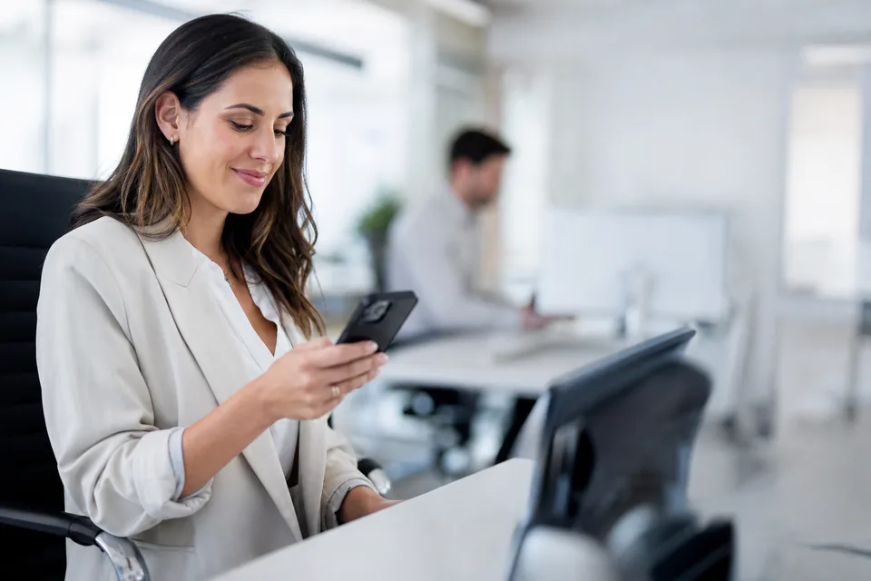 Sales rep at an office desk reading a reply from a lead on her phone