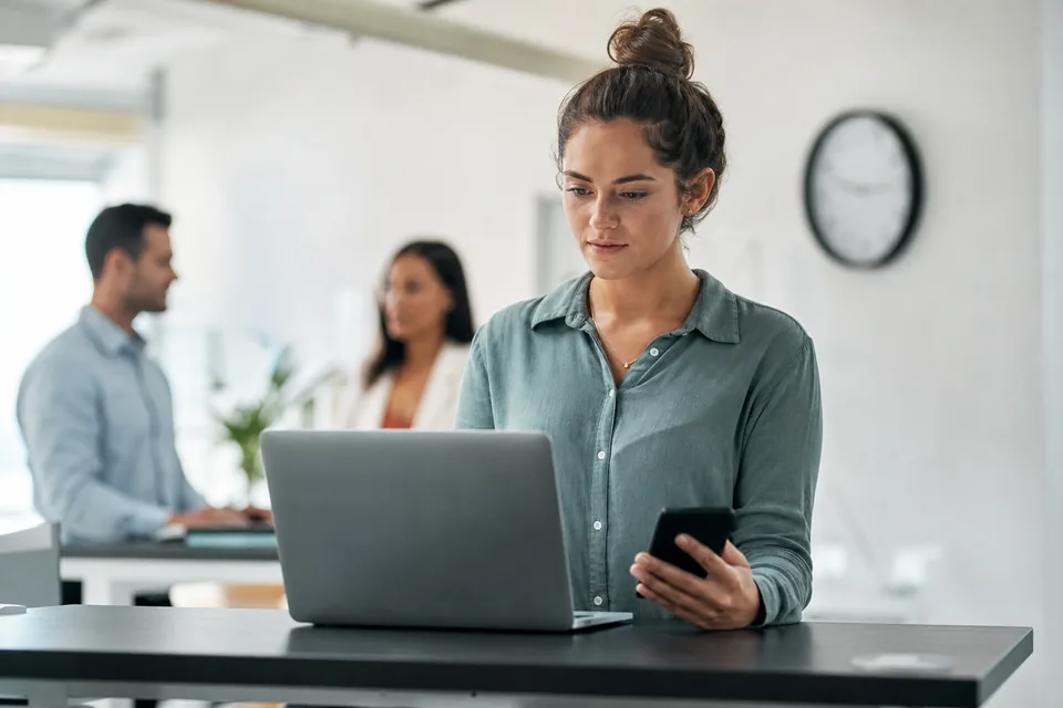Operations lead scheduling a text campaign on a laptop while holding a phone